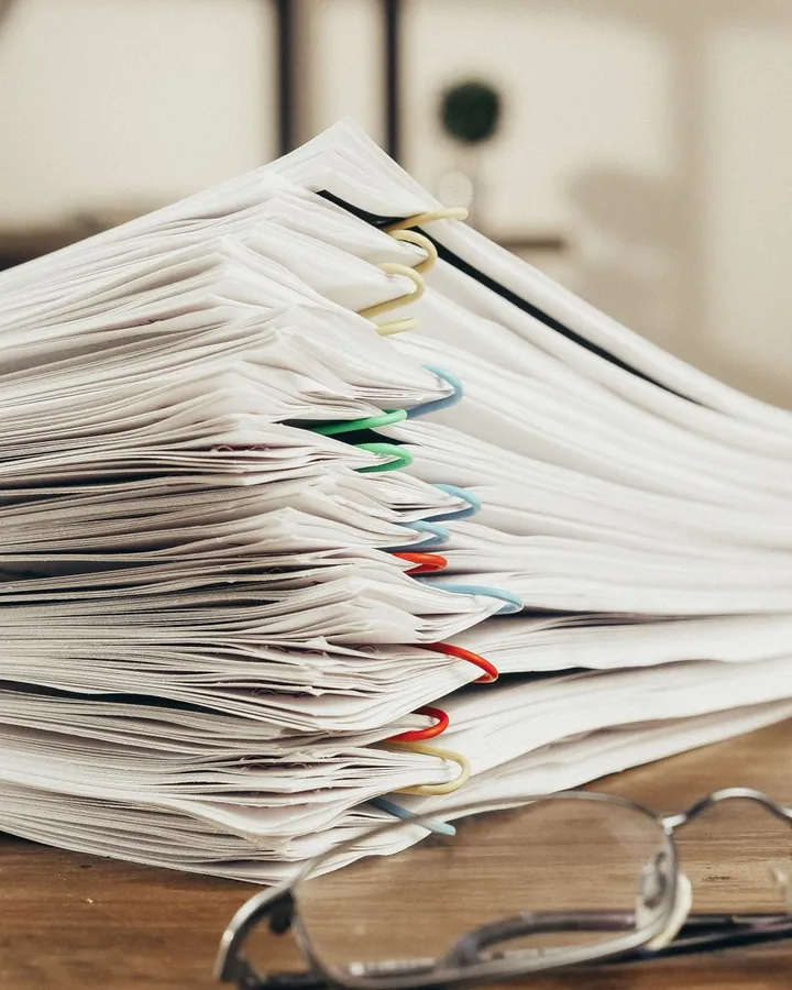 Une pile de dossiers annotés et des lunettes de lecture; image d'ambiance