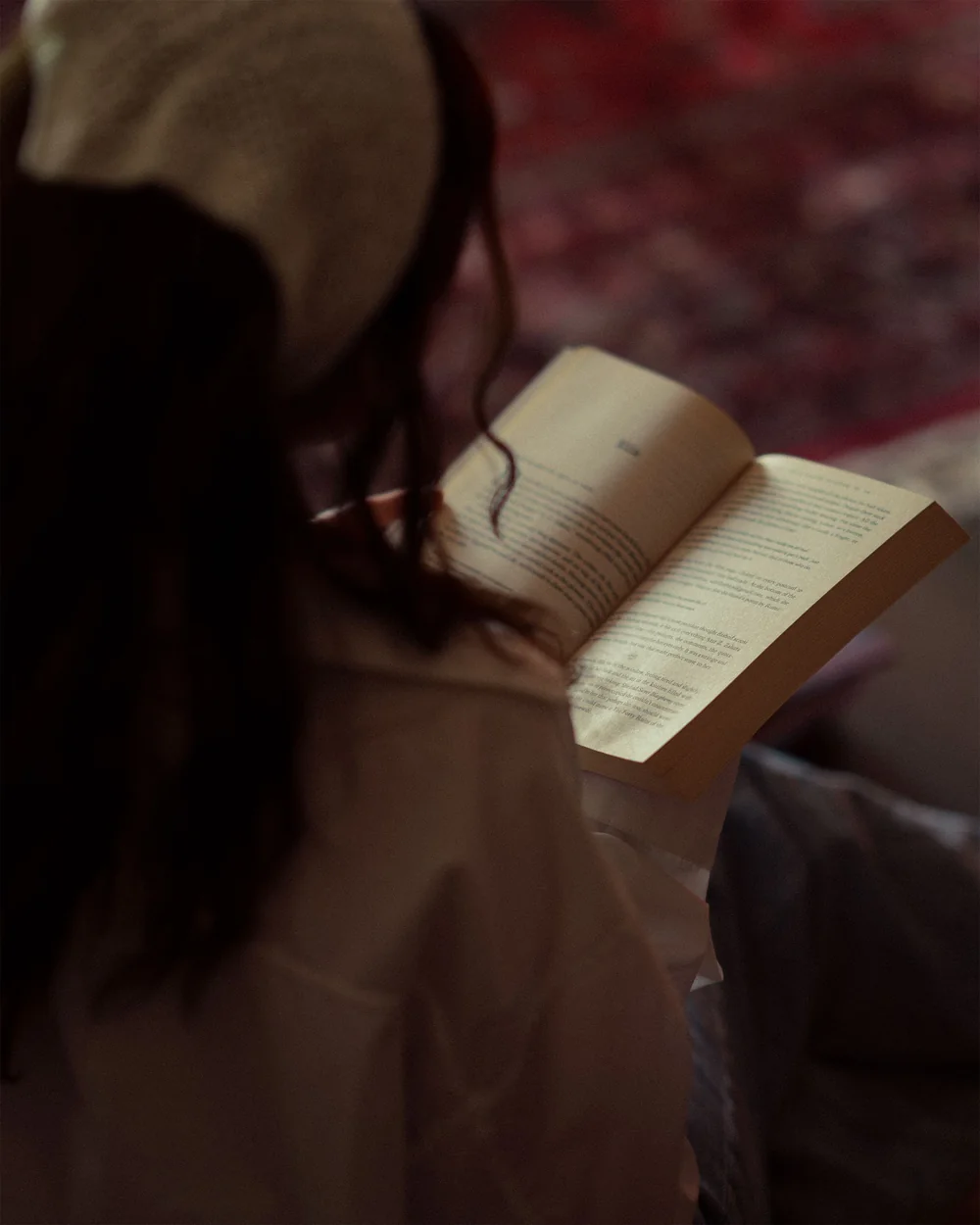Une personne vue de dos qui lit un livre, par-dessus son épaule; image d'ambiance