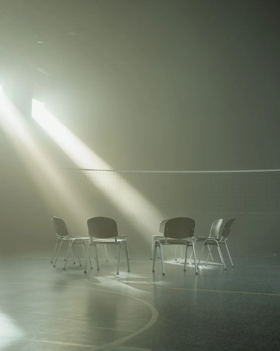 Quatre chaises vides placées en cercle dans un rai de lumière; image d'ambiance